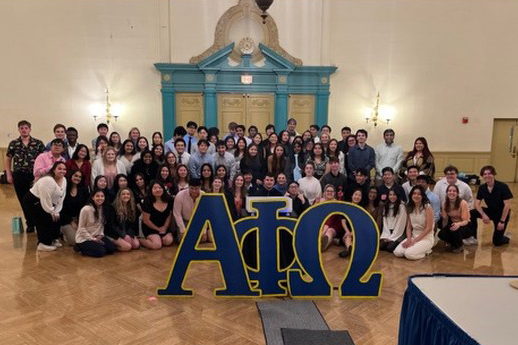 The "Pitbull Class" of pledges of Alpha Alpha chapter of Alpha Phi Omega at the University of Illinois Urbana-Champaign poses as a group behind some large wooden Greek letters for Alpha Phi Omega in Fall 2022. 